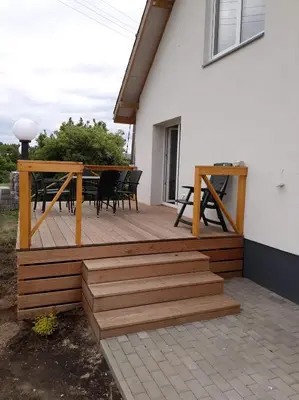 a wooden deck with a table and chairs on a house at Kaimo Vila “Padange” in Kančėnai