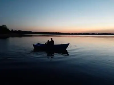 two people in a boat on a lake at sunset at Kaimo Vila “Padange” in Kančėnai