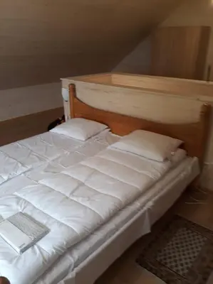 a white bed with a wooden headboard and two pillows at Kaimo Vila “Padange” in Kančėnai