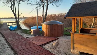 a wooden deck with a hot tub and a gazebo at Kaimo Vila “Padange” in Kančėnai