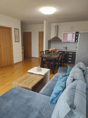 a living room with a blue couch and a table at Klaipėdos 99 Apartamentai in Panevėžys