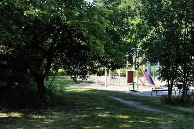 a park with a playground with a bench and trees at Kaminkelio apartment 44 in Vilnius