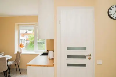a door in a kitchen with a table and a clock at Chill&Go Premium in Kaunas