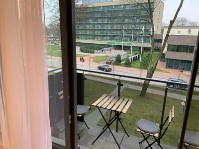 a balcony with a table and chairs and a building at Brolių studija in Druskininkai