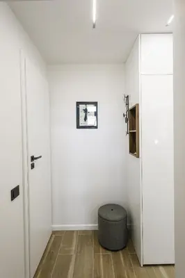 a white room with a ottoman in front of a door at City Center Apartment in Siauliai in Šiauliai