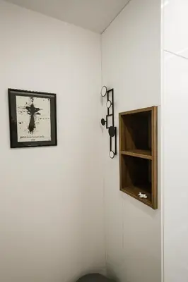 a white wall with a picture and a shelf at City Center Apartment in Siauliai in Šiauliai