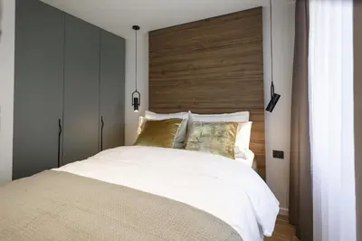 a bedroom with a large white bed with a wooden headboard at City Center Apartment in Siauliai in Šiauliai