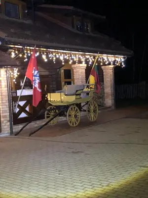 a horse drawn carriage parked outside a building with lights at Skliausčių laisvalaikio centras in Skliausciai