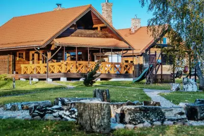 a large wooden house with a large porch at Skliausčių laisvalaikio centras in Skliausciai