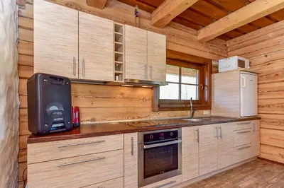 a kitchen with wooden cabinets in a log cabin at Skliausčių laisvalaikio centras in Skliausciai