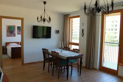a dining room with a table and chairs and a television at Ruta Marija in Druskininkai