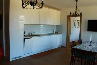 a kitchen with white cabinets and a dining room table at Ruta Marija in Druskininkai