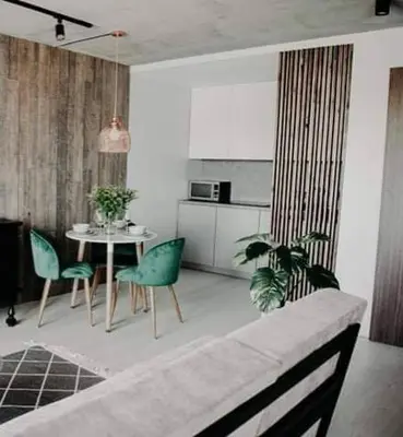 a living room with a table and green chairs at ERTA Anykščių Namai in Anykščiai