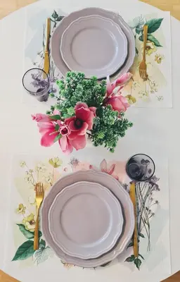 a table with plates and forks and flowers on it at Julia apartments next to AQUA PARK in Druskininkai