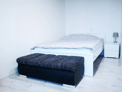 a white bed with a black ottoman in a room at Black & White Studio in Anykščiai