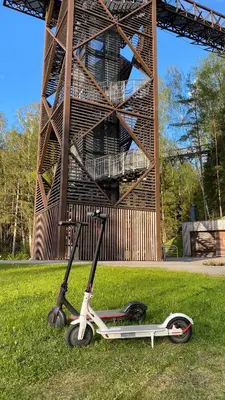 a scooter parked in the grass in front of a tower at Black & White Studio in Anykščiai