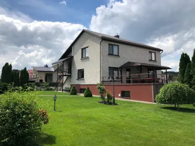 a large house with a yard with green grass at Arvydo Gylio sodyba in Ignalina
