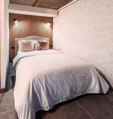 a bedroom with a large white bed with a brick wall at Apartamentai Biržuose, cozy garage in Biržai