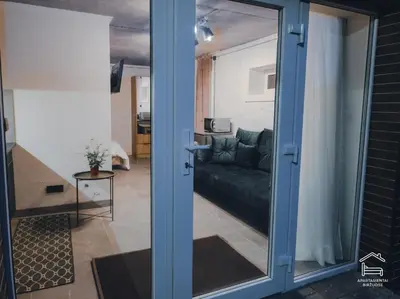 a sliding glass door to a living room with a couch at Apartamentai Biržuose, cozy garage in Biržai