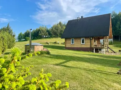 a house with a black roof on a grass field at Miguičionių sodyba in Migučionys