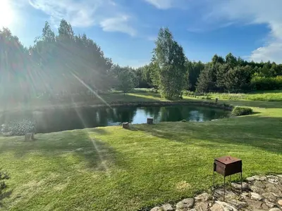 a pond in a grassy field with the sun shining at Miguičionių sodyba in Migučionys