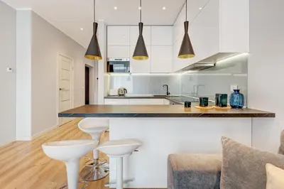 a kitchen with white cabinets and white stools at HaPPy Inn Emporia, Self chek-in, Parking in the underground garage in Vilnius