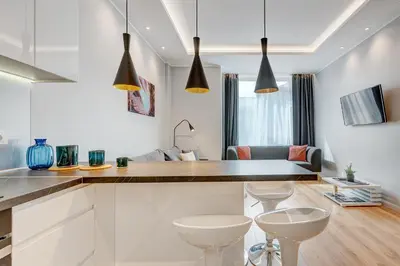 a kitchen with white cabinets and a counter with stools at HaPPy Inn Emporia, Self chek-in, Parking in the underground garage in Vilnius