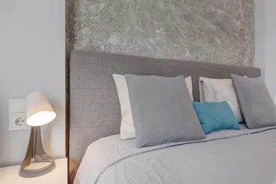 a bedroom with a bed with a gray headboard and pillows at HaPPy Inn Emporia, Self chek-in, Parking in the underground garage in Vilnius
