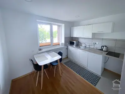 a kitchen with white cabinets and a table and a window at Apartamentai Biržuose, double bedroom and single bedroom Apartments in Biržai