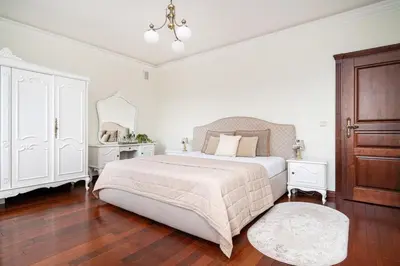 a white bedroom with a large bed and a dresser at Old Town Gate Residence in Vilnius