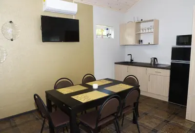 a dining room with a table and a kitchen at Smėlio Apartamentai in Anykščiai