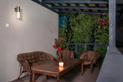 a patio with a table and chairs and a green wall at Smėlio Apartamentai in Anykščiai