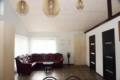 a living room with a leather couch and a window at Smėlio Apartamentai in Anykščiai