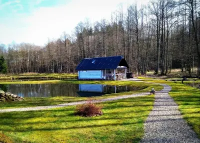 a house with a solar roof next to a pond at White homestead in Sumiliszki