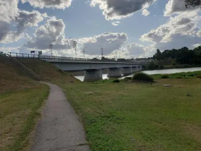 a bridge over a river with a grass field at Apartamentai pas Danutę in Prienai