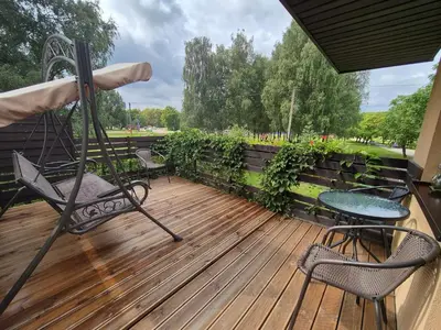 a deck with two chairs and a table and an umbrella at Apartamentai pas Danutę in Prienai