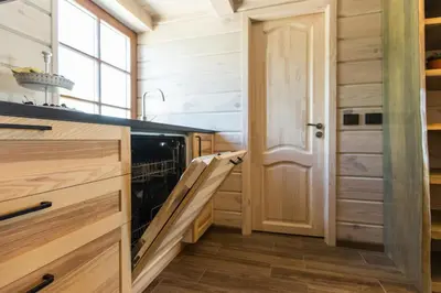 a kitchen with wooden cabinets and a dishwasher at Family house Vila Rica in Ricieliai