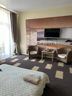 a hotel room with a bed and chairs and a television at Sija's house in Kaunas