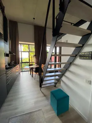 a living room with a staircase and a table at G - Owl Jazz -Modern loft type apartment 18 with big roof terrace and free private parking in Kaunas