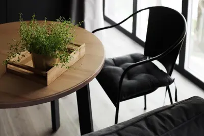 a wooden table with a potted plant and a black chair at G - Owl Jazz -Modern loft type apartment 18 with big roof terrace and free private parking in Kaunas