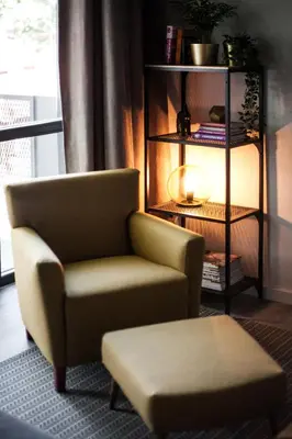 a chair and a stool in a living room at G - Owl Jazz -Modern loft type apartment 18 with big roof terrace and free private parking in Kaunas