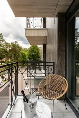 a balcony with a chair and a table with wine glasses at Modern boutique apartment in the city center in Druskininkai