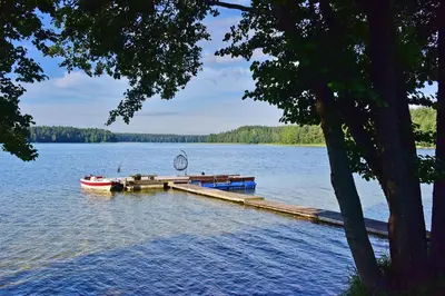 a small boat at a dock on a lake at Šeimos namelis - Mindūnų sodyba in Mindūnai