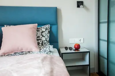 a bed with a pink pillow and a side table at Penthouse in the City Center in Vilnius