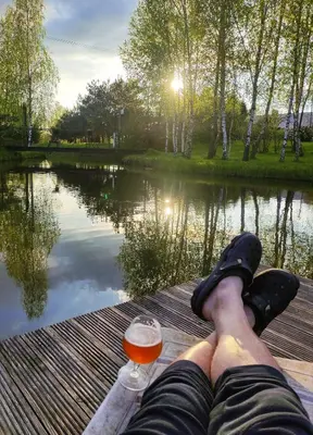 a person sitting on a dock with a glass of wine at Kliukai in Dubingiai