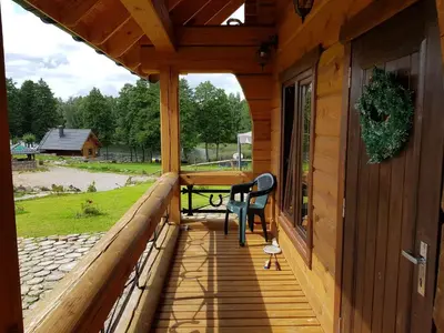 a porch of a wooden cabin with a table and a bench at Namukas su ežero pakrante Trakai ,Viesų vila in Salkininkai