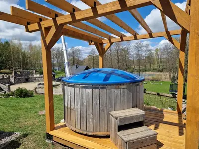 a wooden gazebo with a trash can on a deck at Namukas su ežero pakrante Trakai ,Viesų vila in Salkininkai