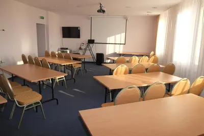 a classroom with tables and chairs and a screen at Hotel Angelas in Utena