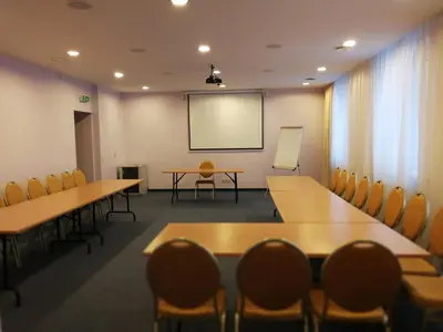 a conference room with tables and chairs and a screen at Hotel Angelas in Utena