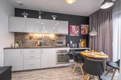 a kitchen with white cabinets and a table and chairs at Vilnius city best view apartments in Vilnius